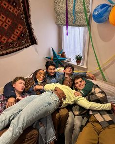 a group of people laying on top of a bed in a room with balloons hanging from the ceiling