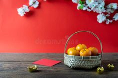 a basket filled with oranges sitting on top of a wooden table next to flowers