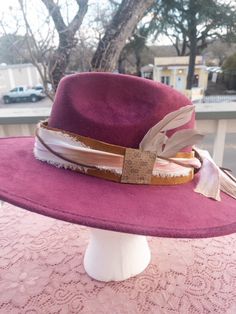 This hatband is gorgeous and has just a little extra added to it. The band is 22.5" x 1.5" and has adjustable ties in the back so it can fit hats from 22.5-34". The bottom layer is one of our favorite leathers, a metallic toasted bronze pink. Very subtle but gorgeous! The designer has then used two types of silk ribbons that complement the leather and really bring the color to life. The brown suede lace adds a nice complete to complete the top layer. As if that wasn't enough...we have added a sm Adjustable Flat Crown Hat For Fall, Adjustable Wide Brim Top Hat For Fall, Adjustable Flat Crown Fedora For Fall, Fitted Hat Bands For Western-themed Events, Adjustable Fedora Felt Hat For Fall, Adjustable Brown Fedora Felt Hat, Vintage Adjustable Hats For Country Events, Vintage Adjustable Hat Bands For Fall, Vintage Fedora For Festival