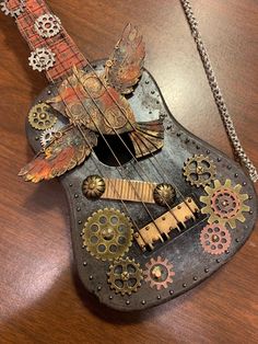 an old guitar with gears attached to it's neck on top of a wooden table