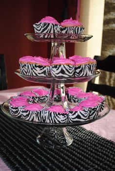 three tiered trays with cupcakes and pink frosting on them sitting on a table