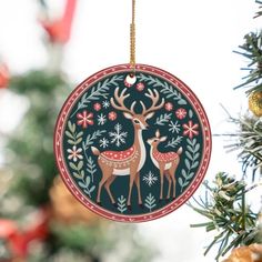 an ornament hanging from a christmas tree decorated with deers and snowflakes