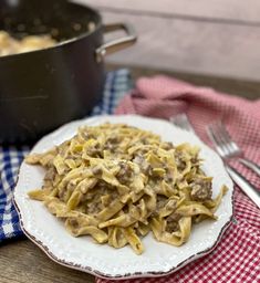 a white plate topped with pasta next to a skillet filled with meat and sauce