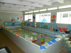 an indoor swimming pool with toys on the floor and in the water for children to play