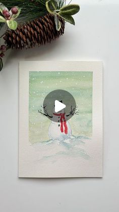 a christmas card with a snowman wearing a red scarf and a pine cone in the background