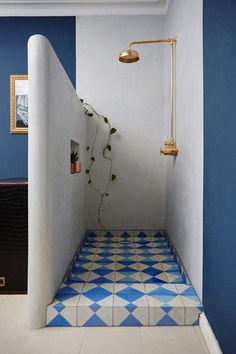 a blue and white tiled bathroom with gold faucet, shower head, and tile floor