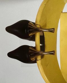 two pairs of black high heeled shoes are on a yellow coat rack with gold handles