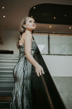 a woman standing on an escalator in a dress