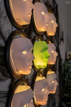 many white mannequin heads are lit up against a wall with lights on them