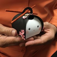 a person holding a small black and white object with pink flowers on it's head