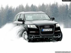 an suv driving through the snow with trees in the background