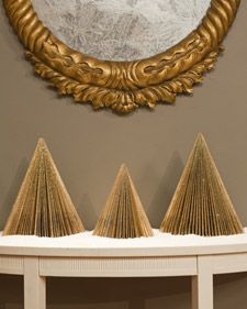 three gold paper cones are sitting on a shelf in front of a round mirror and wall