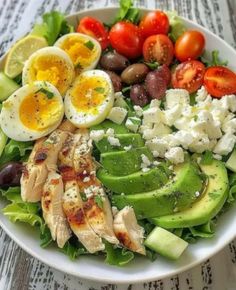 a salad with chicken, avocado, tomatoes, olives and eggs