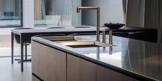 a kitchen with black counter tops and gold faucets on the sink, along with chairs