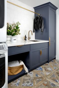 a kitchen with blue cabinets and white counter tops, an oven door is open to reveal the washer and dryer