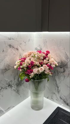 a vase filled with pink and white flowers on top of a counter