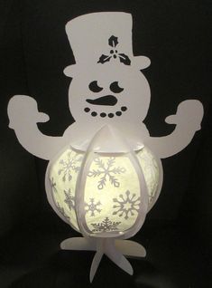 a paper snowman holding a lit up lantern