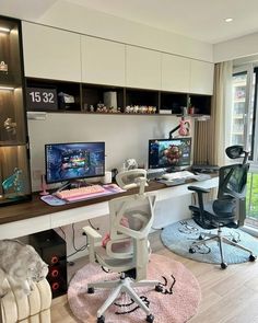 a desk with two computer monitors and a chair in front of it, next to a window