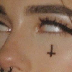 a woman's nose with cross tattoo on it