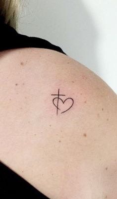 a woman's shoulder with a heart and cross tattoo on the back of her arm