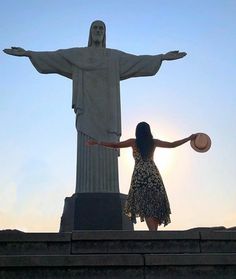 a woman standing in front of the statue of christ