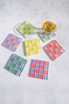 several different colored tiles next to a glass of wine on a white surface with a shadow