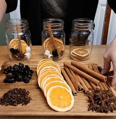 a person is making an assortment of spices on a cutting board with cinnamons, orange slices and black raisins