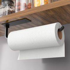 a roll of toilet paper is hanging on the wall next to a shelf with jars