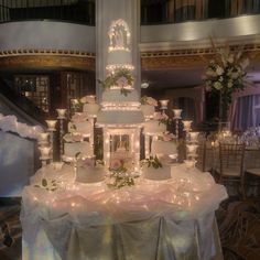 a large wedding cake on top of a table with flowers and candles in front of it