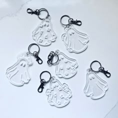 six keychains with different designs on them sitting on a white counter top,