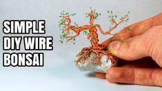 a hand holding a small wire bonsai tree on top of a white surface with the words, simple diy wire bonsai