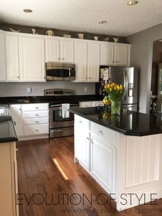 a kitchen with white cabinets and black counter tops