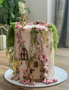 a cake decorated with pink flowers and vines on a table next to a potted plant