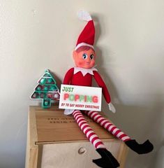 an elf is sitting on top of a dresser holding a sign that says just poping it's to say merry christmas