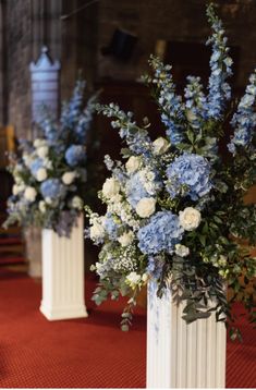 three white vases with blue and white flowers in them on a red carpeted floor