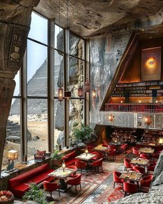 a restaurant with red chairs and tables in front of large windows looking out onto the desert