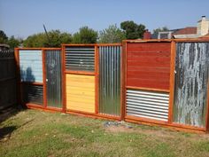 a wooden fence with metal slats on the top and bottom panels painted red, yellow, green, blue, and silver