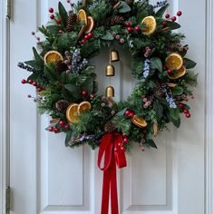 a christmas wreath with oranges and berries hanging on a door