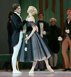 a man and woman in tuxedos standing next to each other on a stage