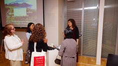 group of women standing in front of a projector screen talking to each other at an event