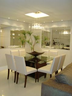 a dining room table with white chairs and a glass top centerpiece on one end