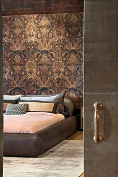 a large bed sitting inside of a bedroom next to a wallpapered headboard