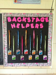 a bulletin board with some tags on it that say backstage helpers and medals hanging from them