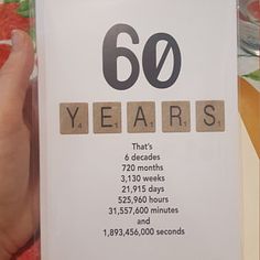 someone is holding up a card with the number sixty years written on it in front of other cards