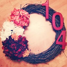 a wreath with flowers and the number forty four on it is displayed in front of a wooden table