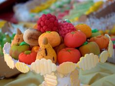 a bowl filled with lots of fruit on top of a table next to cupcakes