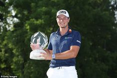 a man holding up a trophy in front of trees