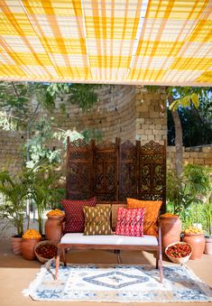 an outdoor seating area with potted plants and pillows