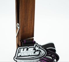 a pair of black and purple leashes sitting on top of a wooden pole next to a logo