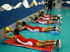 people doing exercises on exercise mats in a gym with one man holding a medicine ball